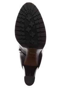 Suela de zapato de cuero negro con un patrón de goma texturizada que presenta crestas horizontales y formas de cruz para mayor agarre. Detalles visibles en costura color marrón claro.