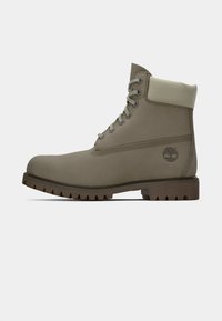 Botine din piele taupe, cu șireturi, cu guler căptușit și talpă robustă, logo-ul Timberland embosat pe lateral.