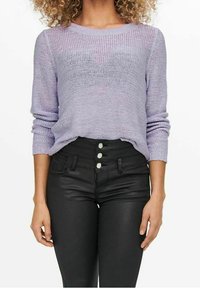 Vaaleanpunainen neulottu pusero, jossa pitkät hihat, yhdistetty korkeavyötäröisiin mustiin farkkuihin, joissa on neljä nappia ja sileä pinta.