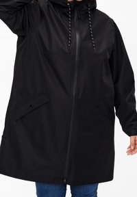 Black waterproof rain jacket with a zip front, adjustable hood, and two front pockets. Features a relaxed fit and elastic cuffs.