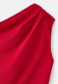 Tejido de vestido rojo con una textura suave, que presenta un detalle de nudo drapeado en el hombro. El diseño tiene un corte asimétrico.