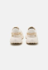 Beige sportieve schoenen met een textiele bovenkant, een gevoerde kraag en een versterkte hak. Voorzien van logo-accents en een groefachtige rubberen buitenzool.