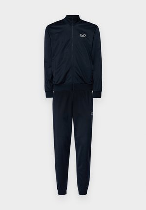 Chándal azul marino que consiste en una chaqueta con cremallera y pantalones con cinturilla elástica, ambos con una textura suave y un branding sutil.