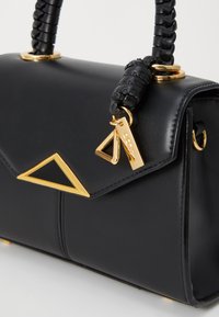 Borsa a tracolla in pelle nera con un'accenno triangolare dorato, tracolla intrecciata e hardware dorato. Presenta una chiusura a pattina e una texture liscia.
