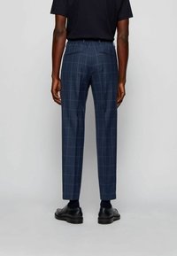 Námořnické kostkované kalhoty s uvolněným střihem, s elastickým pasem, dvěma zadními kapsami a zúženými nohavicemi, doplněné černými botami.