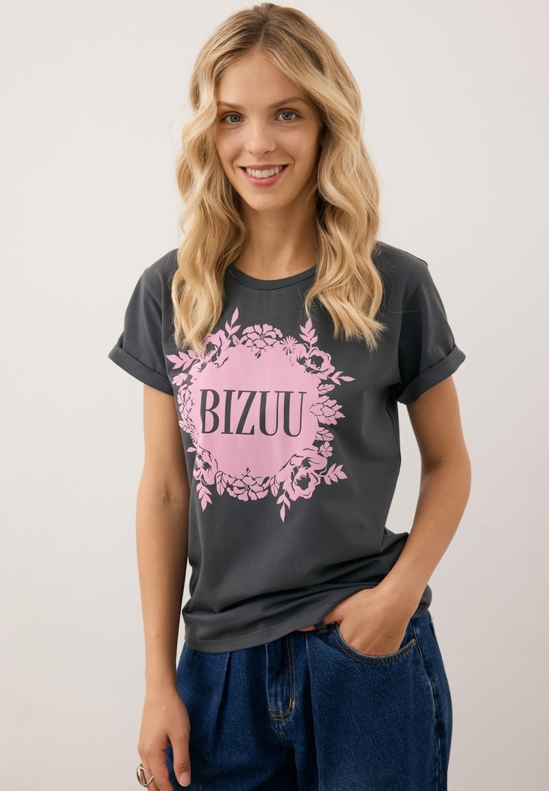 Grijze t-shirt met korte mouwen met een roze bloemenontwerp en het woord "BIZUU" in vetgedrukte zwarte letters. Zachte stof en een ontspannen pasvorm.