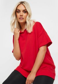 Röd oversized T-shirt i mjuk bomull, med korta ärmar och avslappnad passform. Texturerad tyg med rund halsringning och minimal sömnad.