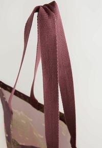 Maroon tote bag with textured, woven fabric straps; features a patterned main body and an open top design.