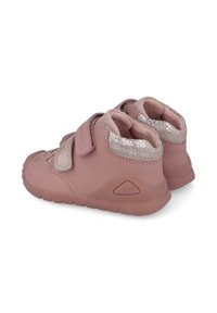 Zapatillas infantiles rosas con un acabado texturizado, que cuentan con dos correas de velcro y un acento brillante e iridiscente. Suela de goma para agarre.