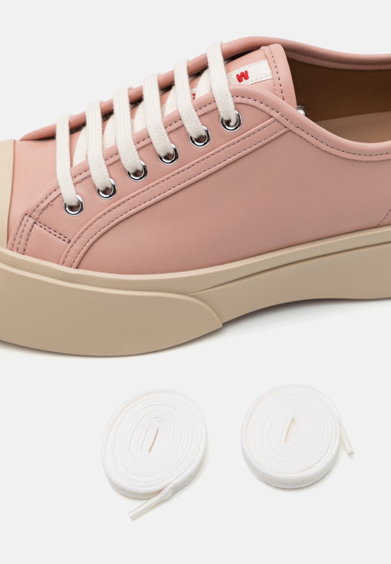 Pink leather sneakers feature a rounded toe, beige rubber sole, and white woven laces. Two additional white laces are included.