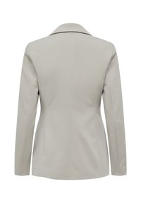 Veste blazer beige sur mesure pour femme, vue de dos avec manches longues et col structuré sur fond blanc.