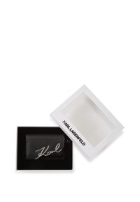 Black leather cardholder with silver signature detail, presented in a white and black branded box with a clear window.