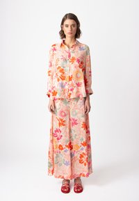 Kvetinový blouse a maxi sukňa v pastelovo ružovej farbe, so živými oranžovými, fialovými a zelenými kvetmi. Ľahký materiál s voľným strihom.
