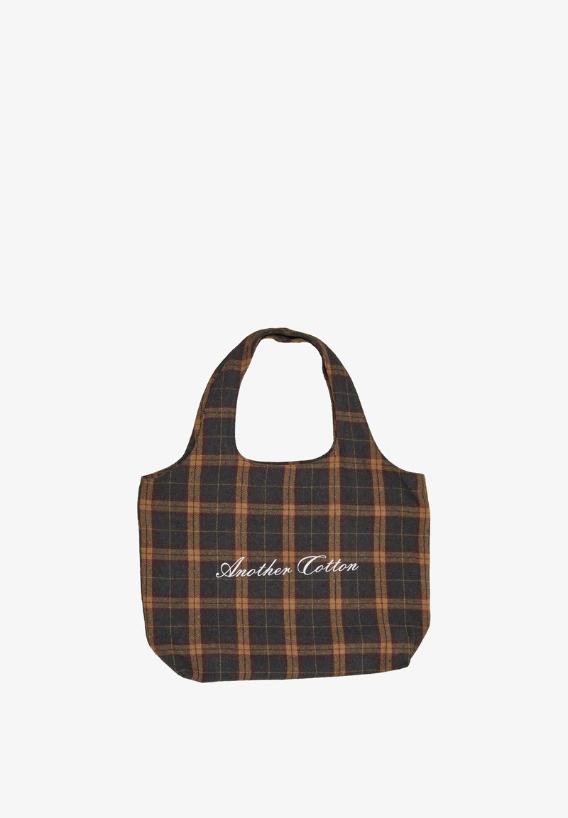 Károvaná taška přes rameno vyrobená z bavlny s tmavě modrými, hnědými a světle oranžovými vzory. Má zaoblenou rukojeť a bílý nápis "Another Cotton."