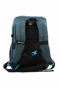 Mochila de tela en color verde azulado con correas de hombro acolchadas, panel de malla y acentos en hebilla azul. Cuenta con un asa superior reforzada y un parche con el logo.