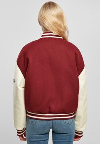 Maroon and cream varsity jacket with ribbed collar and cuffs. Soft wool body and leather sleeves. Elastic waistband. Minimal branding on sleeve.