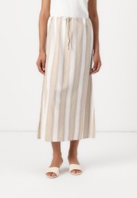 Jupe maxi légère rayée en beige et blanc avec des accents bleu marine, dotée d'une taille à cordon et de fentes latérales pour plus de liberté de mouvement.