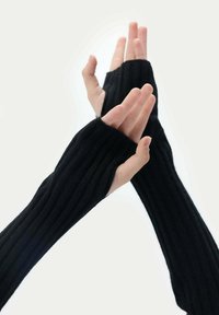 Svarta ribbstickade armvärmare med öppna fingertoppar. Mjuk textur som sträcker sig till handlederna, med en enkel design utan ytterligare hårdvara.