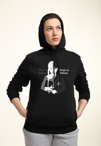 Felpa nera con cappuccio e stampa grafica che raffigura un personaggio che tiene un libro. Il testo recita: "Una volta Addams, sempre Addams."
