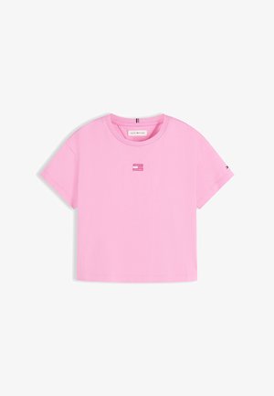 Top court rose à manches courtes avec col rond et petit logo rectangulaire Tommy Hilfiger rose au centre devant et détail drapeau sur la manche.