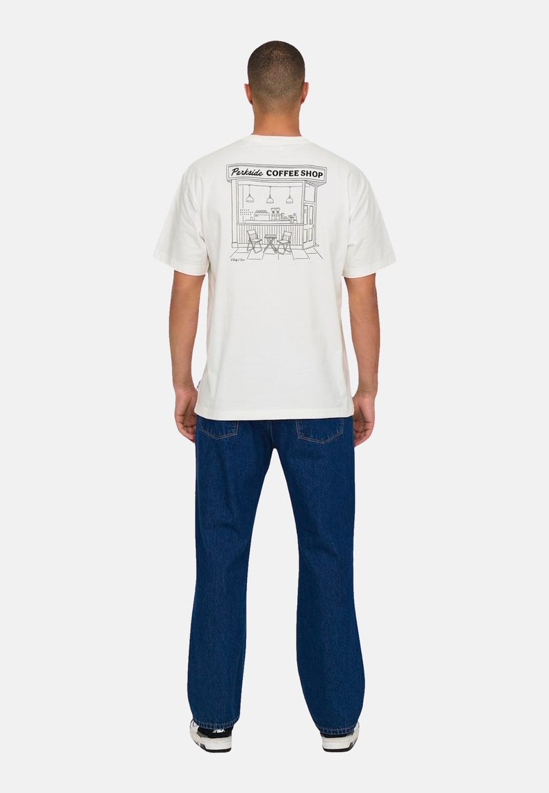 Witte katoenen t-shirt met een lijntekening van een koffiehuis op de achterkant. Gecombineerd met donkerblauwe jeans en sneakers.