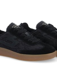 Black sports shoes with a textured upper, suede accents, lace closure, and a brown rubber sole. Features logo detail in gold.