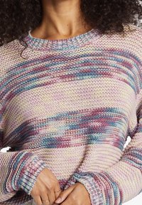 Neulepusero, jossa on monivärinen kuvio pastellin vaaleanpunaisella, sinisellä ja violetilla sävyllä. Resorikaulus ja -hihansuut, joissa on teksturoitu viimeistely.