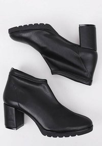 Black ankle boots made of smooth leather with a chunky block heel and a slightly slouched design, featuring a textured sole for traction.