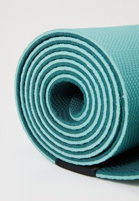 Tyrkis yoga-matte rullet tett, med teksturert, sklisikker overflate med en mørkere kjerne og en svart akcent på enden.