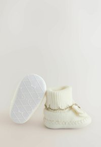 Valged kudum kingad on varustatud soonikuga ääre, dekoratiivse kuldkettide ja lipsu aktsendiga. Tald on tekstureeritud, et tagada haarduvus ja stabiilsus.