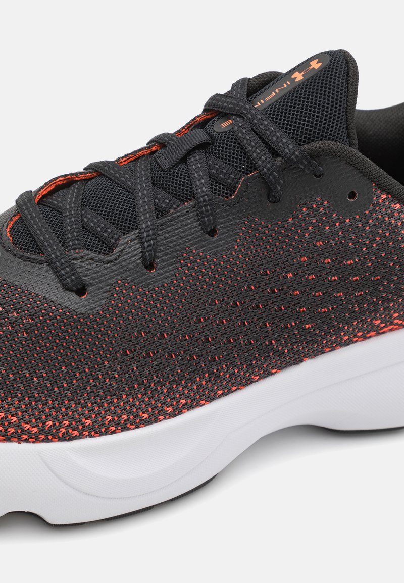 Chaussure de sport en maille noire avec des accents rouges, présentant un dessus texturé, des lacets robustes et une semelle blanche durable pour l'adhérence.