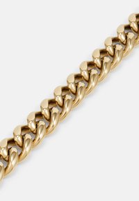 Goldene Armbandkette mit dicken, ineinandergreifenden Gliedern und einer polierten, glänzenden Oberfläche. Glatte Textur mit symmetrischem Design.