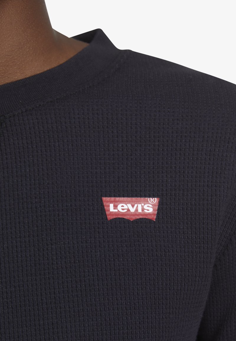 Maglione a costine blu navy con scollo rotondo, dotato di un patch con il logo rosso di Levi's nella zona sinistra del petto.