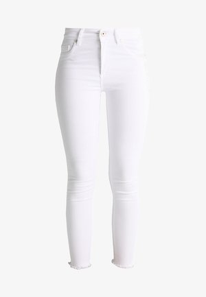 Jeans blancos ajustados de mezclilla. Incluye características como una cintura alta, diseño de cinco bolsillos y un dobladillo deshilachado en los tobillos.