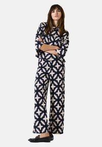 Navy en crème gestreepte tweedelige outfit met een losse top met 3/4 mouwen en wijde broek met geometrische ontwerpen.