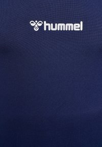 Marineblaue Sportshirt aus strukturiertem Stoff; mit einem weißen "hummel"-Logo auf der Brust. Glattes, enganliegendes Design, geeignet für den Sport.