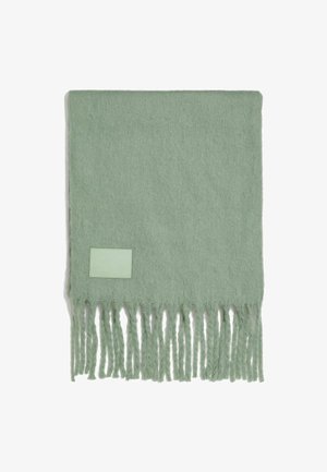 Šviesiai žalia vilnos ir sintetinių skaidulų šalikas su pūkuotais kraštais ir stačiakampiu odiniu akcentu, kuriame kampe įspaustas tekstas „draugai“.