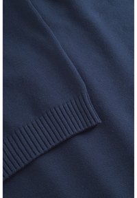 Tumedav sinine kampsun, millel on sile kudumistruktuur. Omab soonikuid mansette ja allserva, rõhutades klassikalist disaini ja ühtlast õmblust kogu ulatuses.