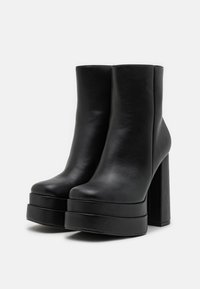 Black leather ankle boots with a smooth texture, chunky high platform, and block heels, featuring a rounded toe and minimalist design.