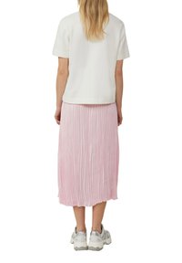 T-shirt en coton blanc à manches courtes, associé à une jupe midi plissée rose et des baskets gris clair.