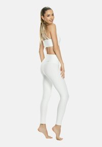 Conjunto de sujetador deportivo blanco y leggings, hecho de material elástico. El sujetador cuenta con tirantes finos; los leggings tienen una cintura alta y un diseño sin costuras.