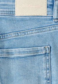 Light blue denim jeans pocket with visible stitching and beige label reading "Street One - Denim All Time Favourite."