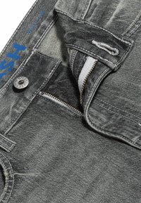 Grå denimjeans med dragkedja, metallknappstängning, och en blå broderad "W31 L32" etikett i midjan. Strukturerad tyg med lätt blekning.