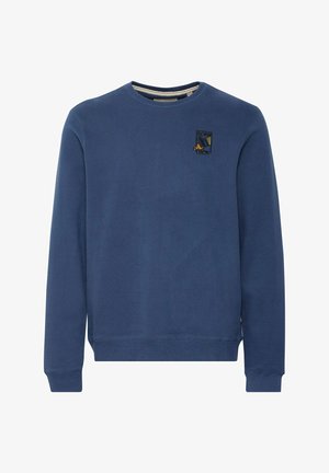 Blå hettegenser laget av mykt stoff, med rund hals, ribbede mansjetter og et brodert logo på brystet. Glatt tekstur.