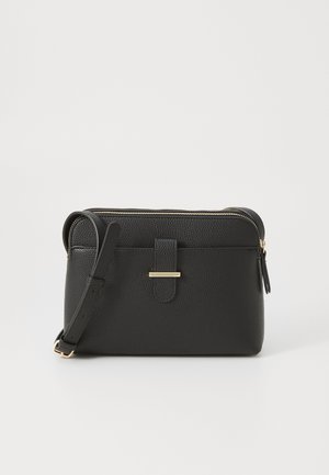 Zwarte leren crossbodytas met korrelstructuur, verstelbare schouderriem, voorste riem met gouden sluiting en bovenste ritssluiting tegen een witte achtergrond.