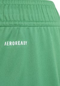 Roheline sportlik lühike püksid pehmest kangast, elastse vöökoha ja valge "AEROREADY" logoga õmbluse juures.