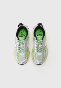 Scarpe da ginnastica argento con accenti verdi, in materiale mesh, con punta arrotondata e suola bianca. I lacci sono grigi e la fodera interna è verde.