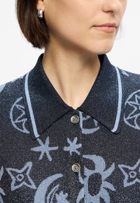 Πουκάμισο με γιακά σε σκούρο ύφασμα με διακριτική γυαλάδα, διακοσμημένο με ανοιχτό μπλε μοτίβα από αστέρια και ουράνια σχέδια; περιλαμβάνει κλείσιμο με κουμπί.