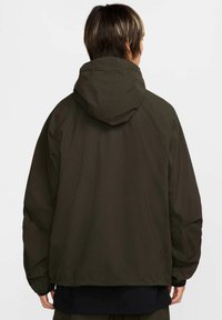Mörkgrön jacka med huva, med en avslappnad passform, slät tyg och synliga sömnadsdetaljer på huvan och axlarna.