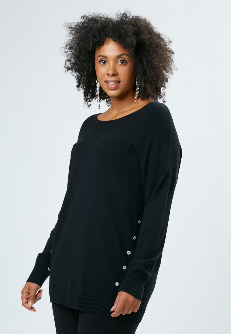 Maglione nero a maniche lunghe con collo rotondo, orlo a costine e bottoni decorativi lungo i lati. Texture morbida e vestibilità rilassata.